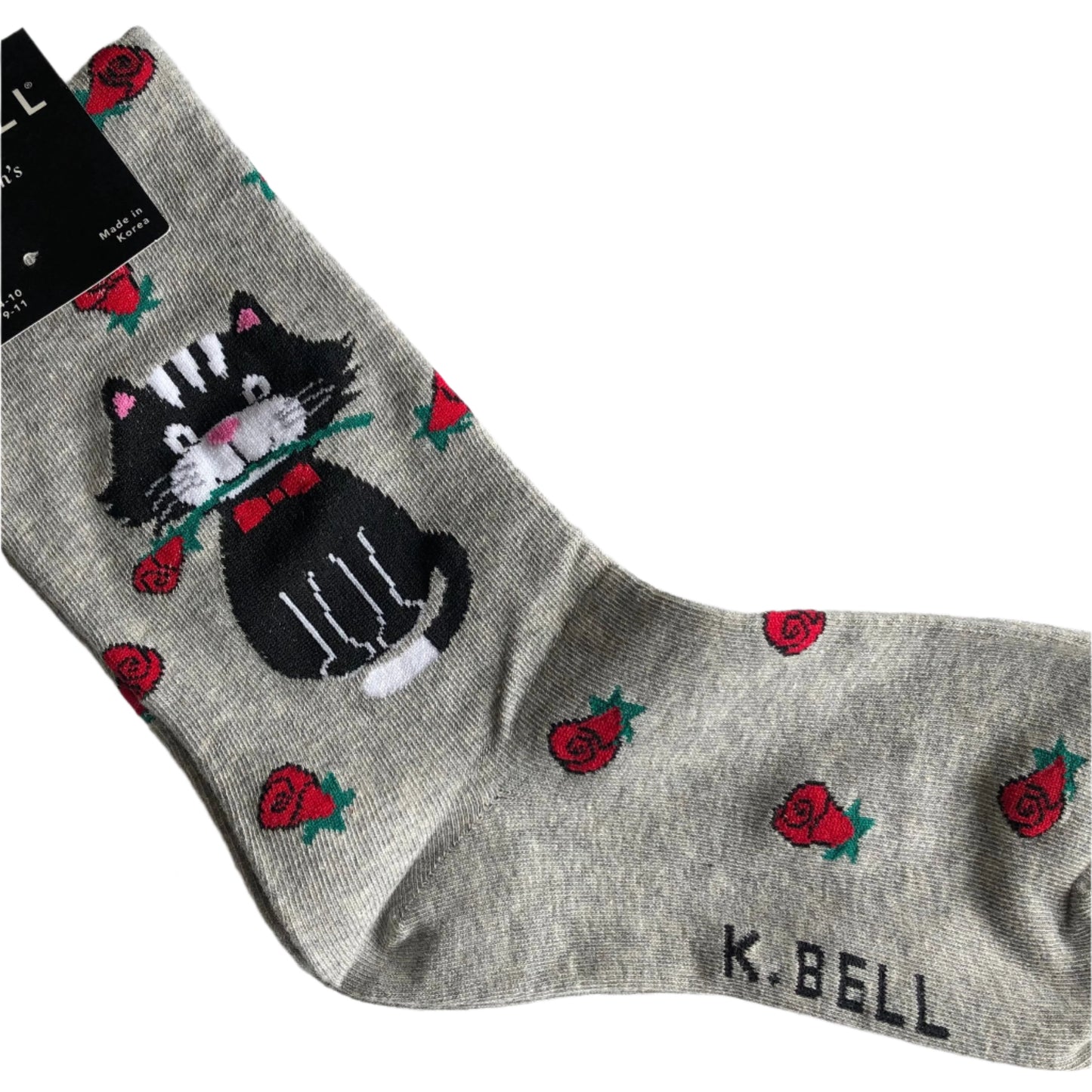 K Bell brand light grey crew sock with red roses all over it and at the ankle a black & white cat with rose in mouth