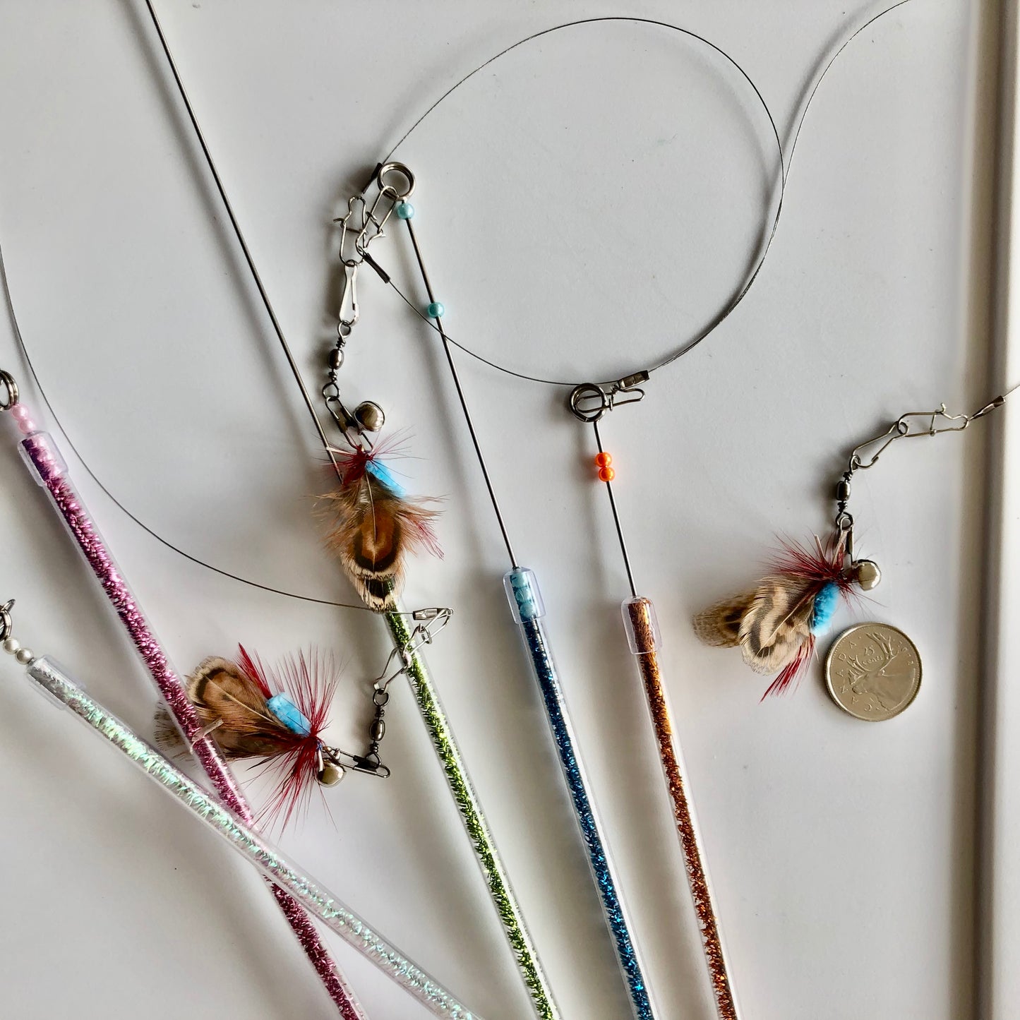 closeup of a few different coloured wands showing the 10" telescopic tip pulled out to different lengths and also the bonus fly fishing attachment beside a quarter to show relative size