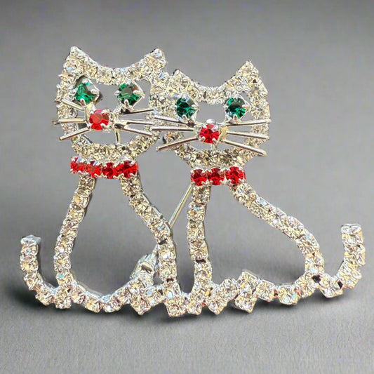 rhinestone cats sitting together with green gem eyes and red rhinestone collar, cute tails, metal whiskers