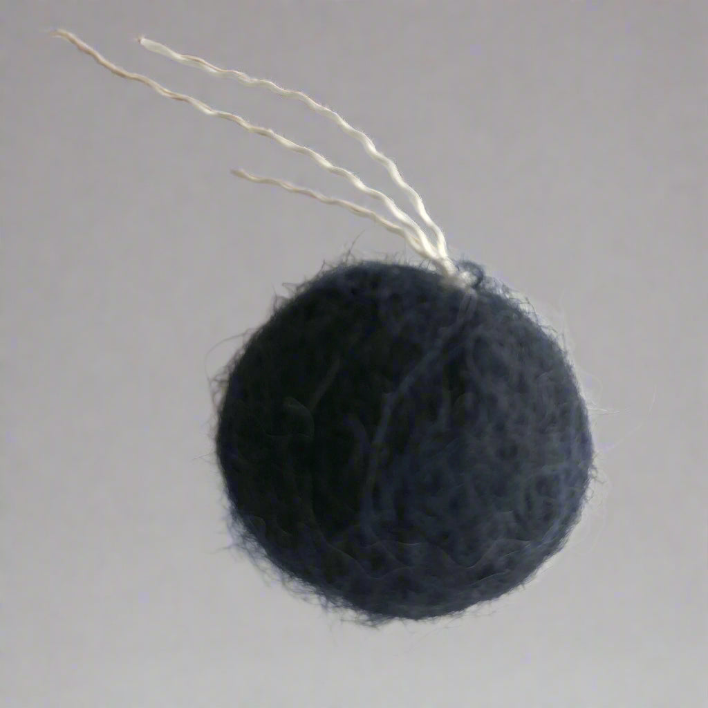 closeup of wool ball with thread "tail" are small enough for a cat to pick up with their mouth to carry or toss, just over an inch (2.5 cm) in diameter