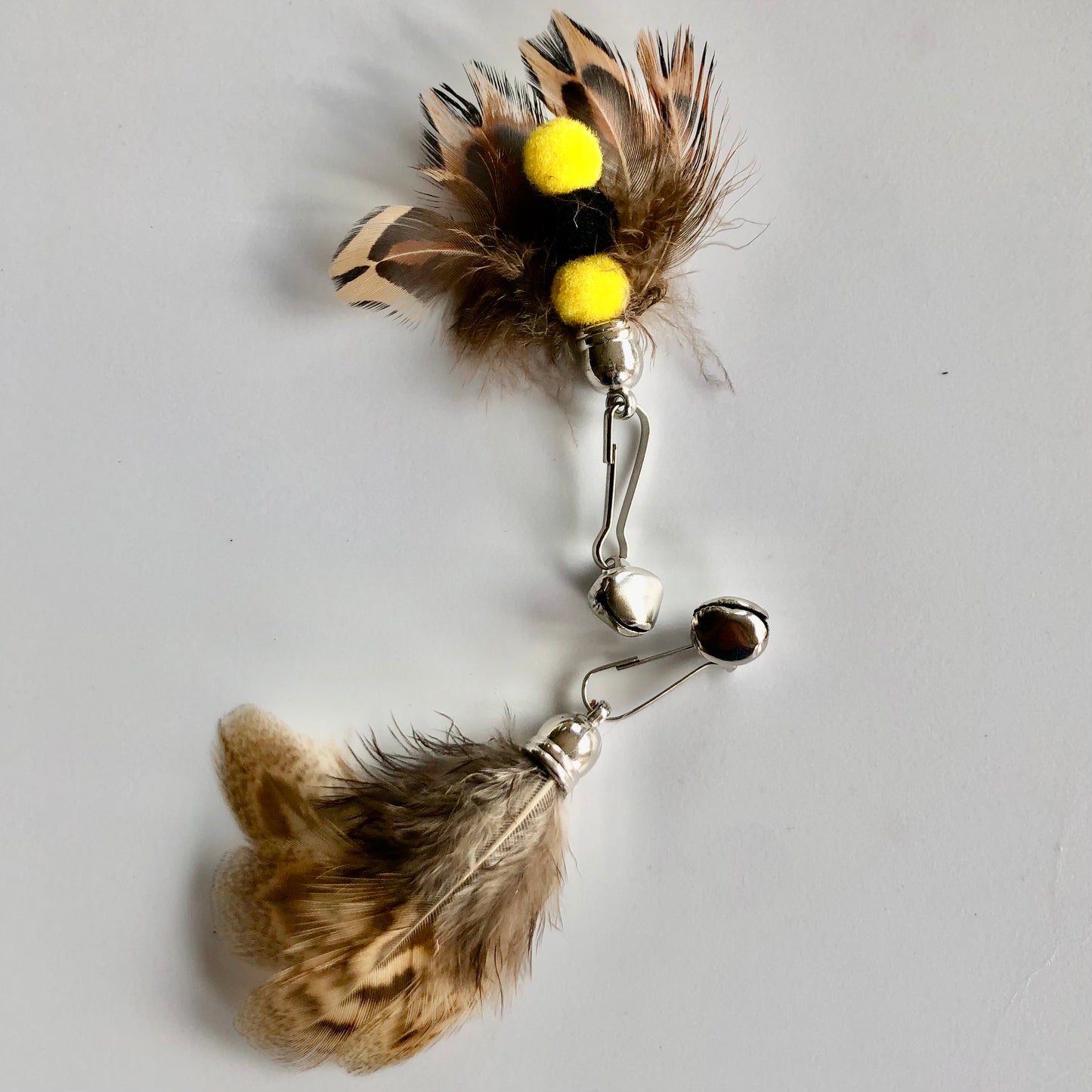 closeup of 2 mini-moth cat toy attachment showing from above with mostly feathers and if you turn it over, 3 small balls and a bell