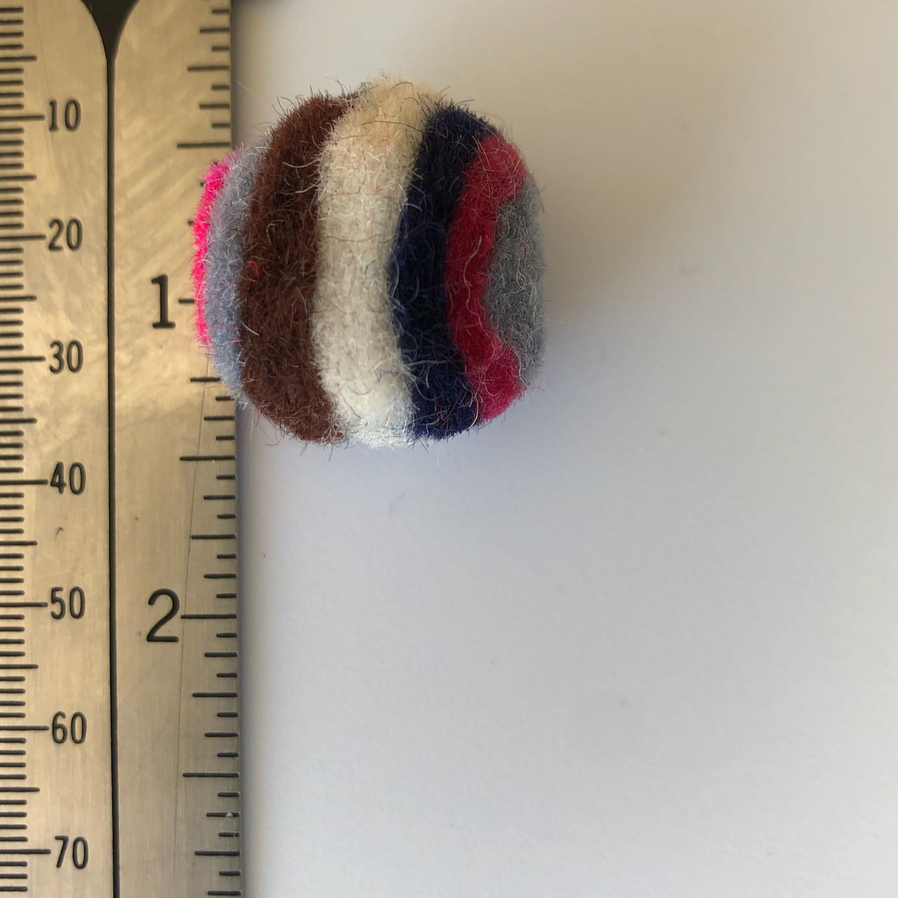 single layered wool ball beside a ruler to show size of 2.5 cm 
